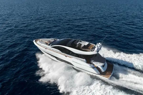 Luxury yacht cruising over waves in clear blue water, showcasing sleek design and spacious deck areas.